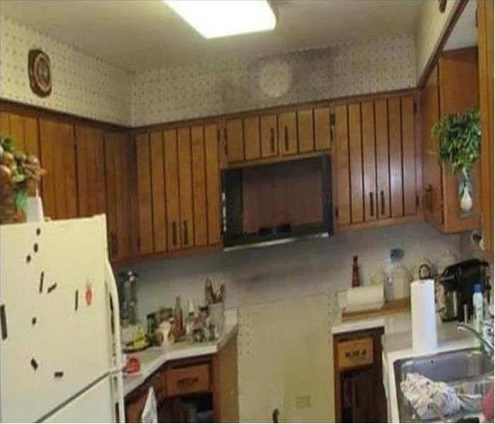 small kitchen with smoke residue above microwave