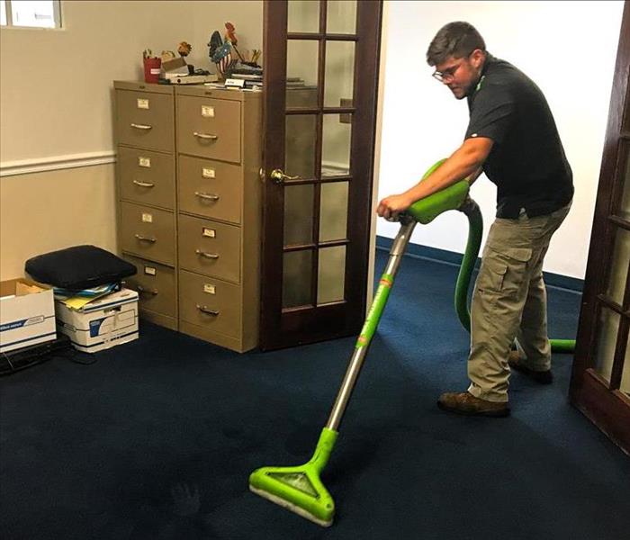 SERVPRO technician using extraction wand to remove water from a carpet
