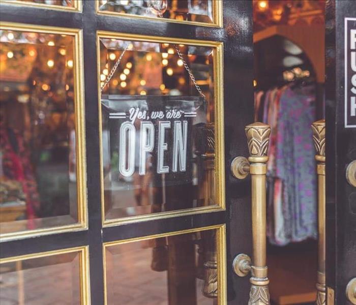 storefront of a brick-and-mortar business with door sign reading yes we are open