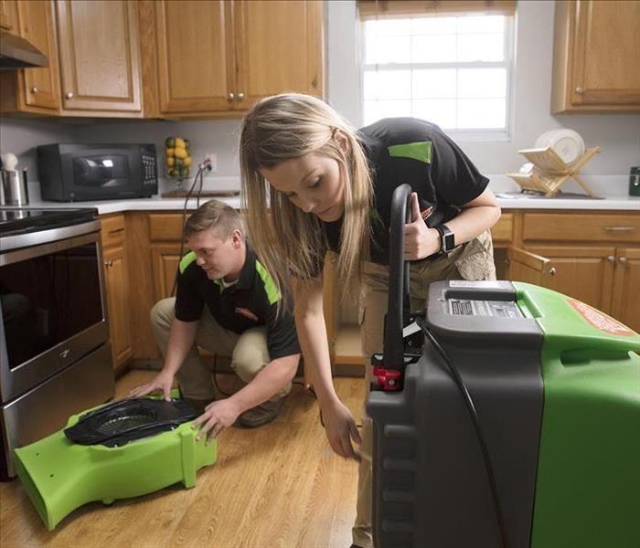 SERVPRO techs setting equipment in a water damaged kitchen