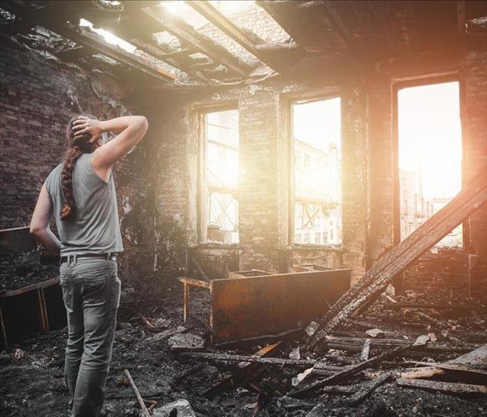 woman looking at the aftermath of a fire in her home